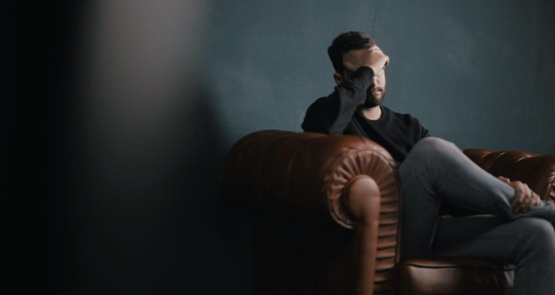 Man looking stressed sat on the sofa